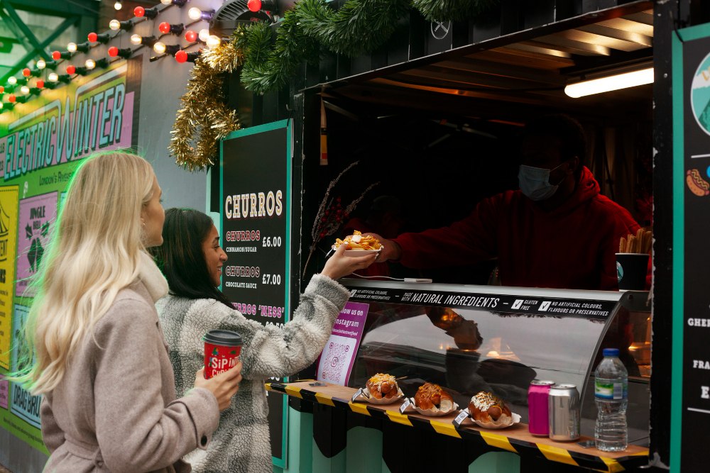 Przygotowanie burgerów we wnętrzu food trucka – kucharz przy grillu