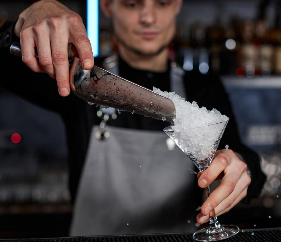 Pokruszony lód wsypywany do szklanego pucharka – przygotowanie deseru lub drinka