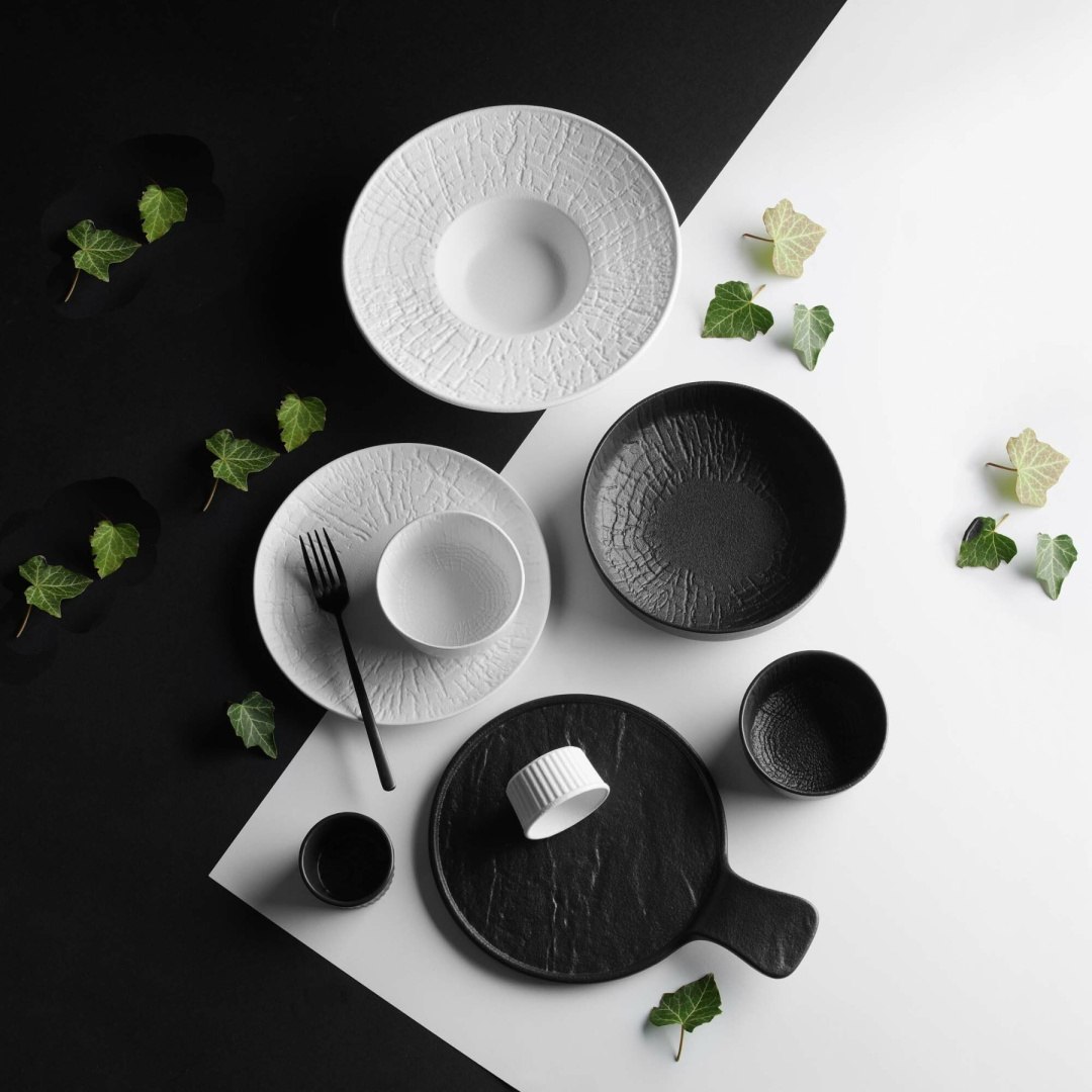 Śnieżnobiała porcelana na świątecznym stole z gałązkami bluszczu, czarną porcelana Crust i srebrnymi sztućcami