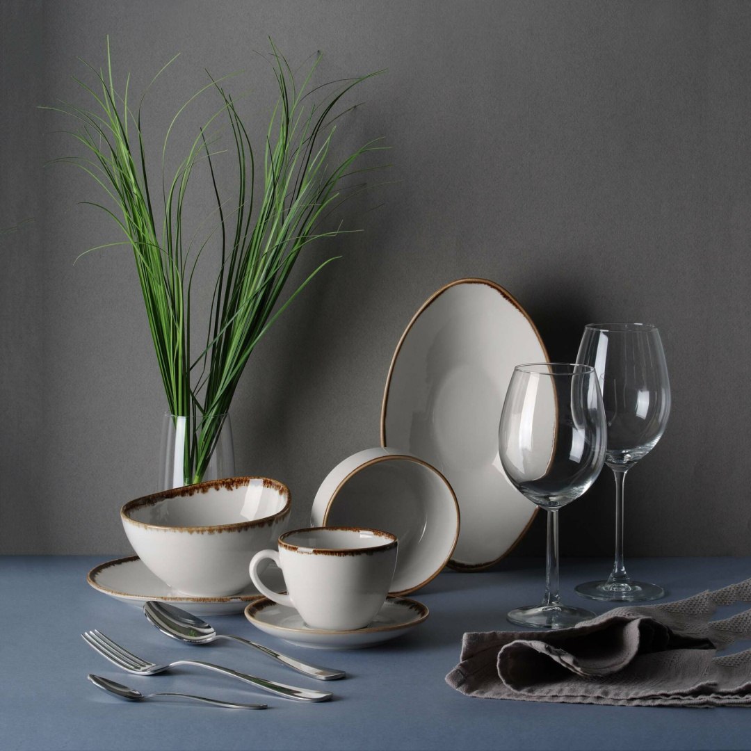 Kremowa porcelana ze złotymi dodatkami i naturalnym obrusem na świątecznym stole