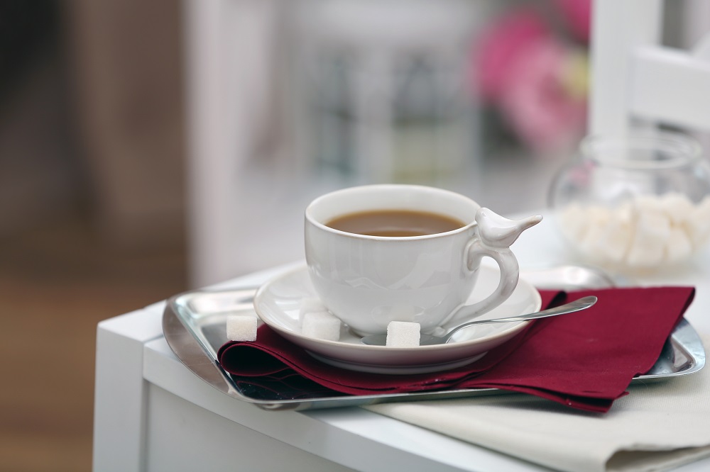 Elegancka filiżanka porcelanowa ze spodkiem, w aranżacji na białym stole