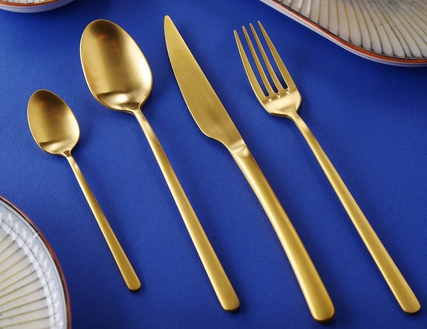 Elegancki zestaw złotych sztućc&oacute;w Amarone Gold na stole bankietowym