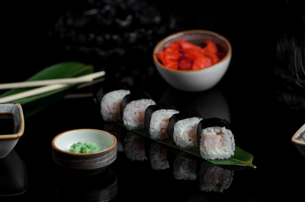 Klasyczne nigiri i maki sushi podane na czarnej kamiennej tacy w nowoczesnym sushi barze